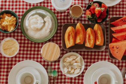 Vibrant breakfast spread featuring fresh fruits, pastries, and dairy on a checkered tablecloth.
