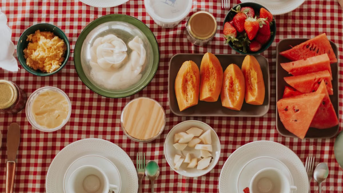 Vibrant breakfast spread featuring fresh fruits, pastries, and dairy on a checkered tablecloth.