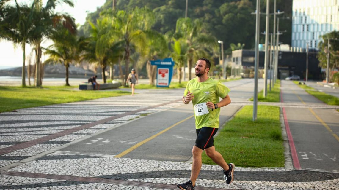 Man running a marathon on a scenic coastal road lined with palm trees.
