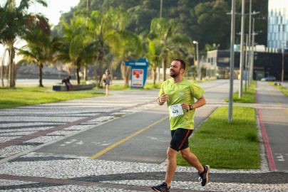 Man running a marathon on a scenic coastal road lined with palm trees.