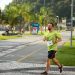Man running a marathon on a scenic coastal road lined with palm trees.