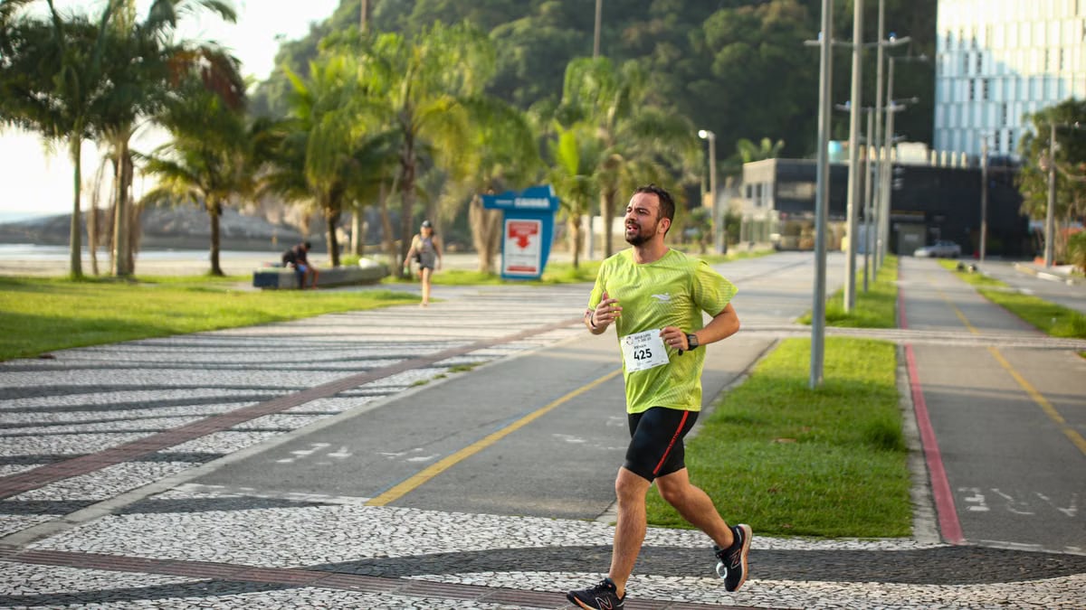 Man running a marathon on a scenic coastal road lined with palm trees.